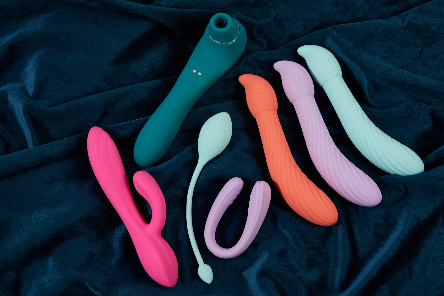 Three colorful vibrators arranged on white fabric, highlighting their smooth texture and design