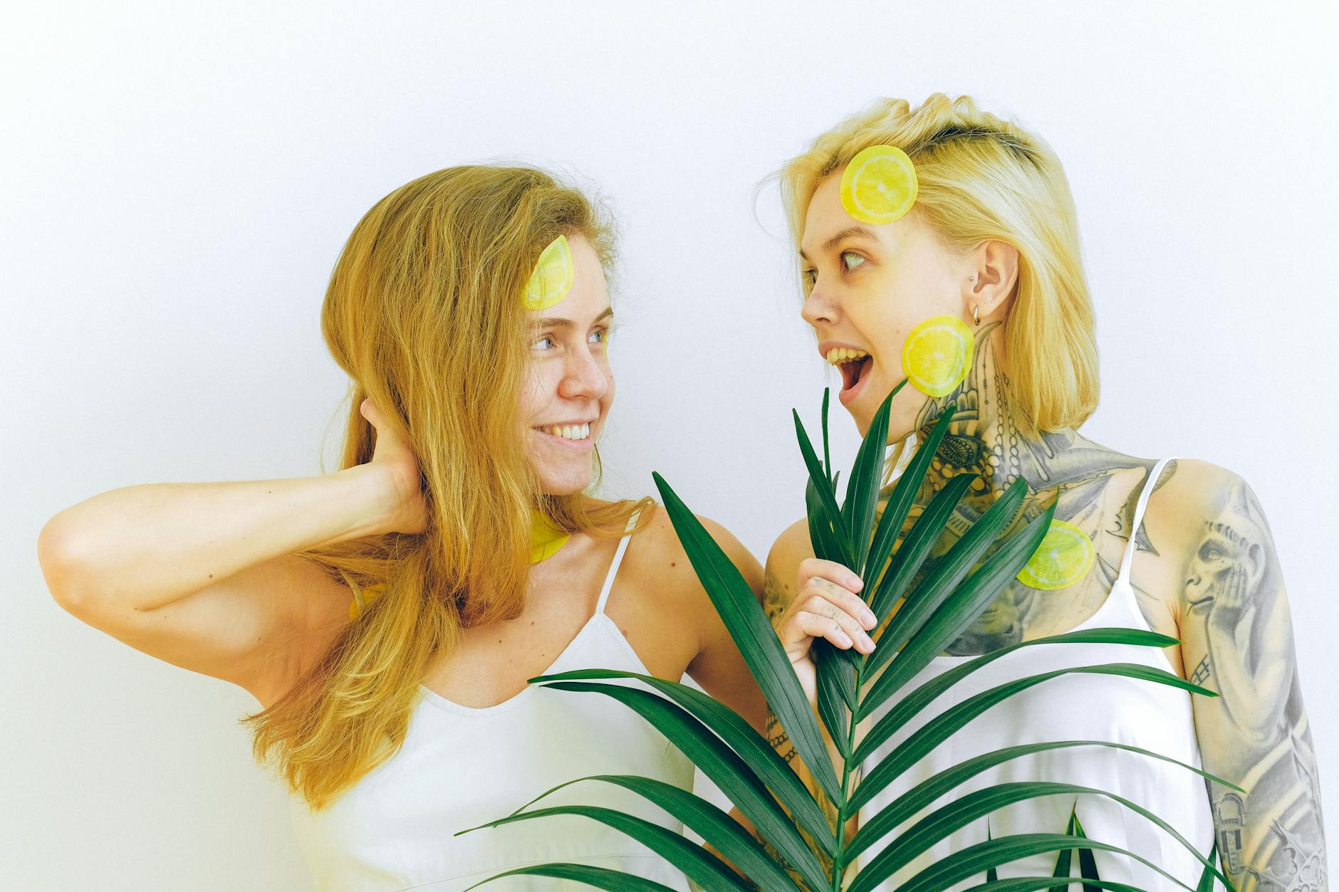 Two women smiling together with lemon slices, expressing joy and connection indoors