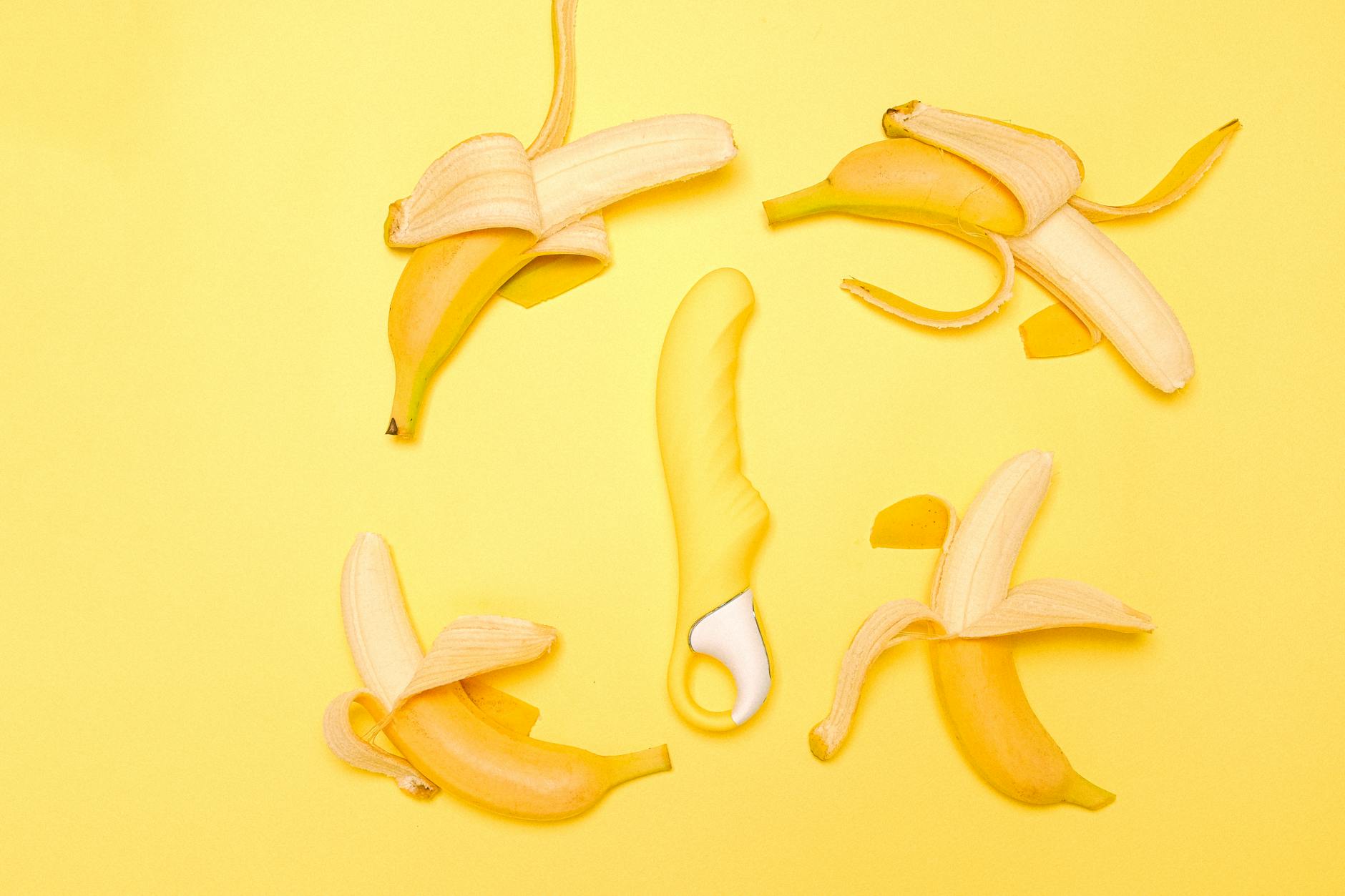 Yellow silicone lemon vibrator surrounded by peeled lemons on a yellow background
