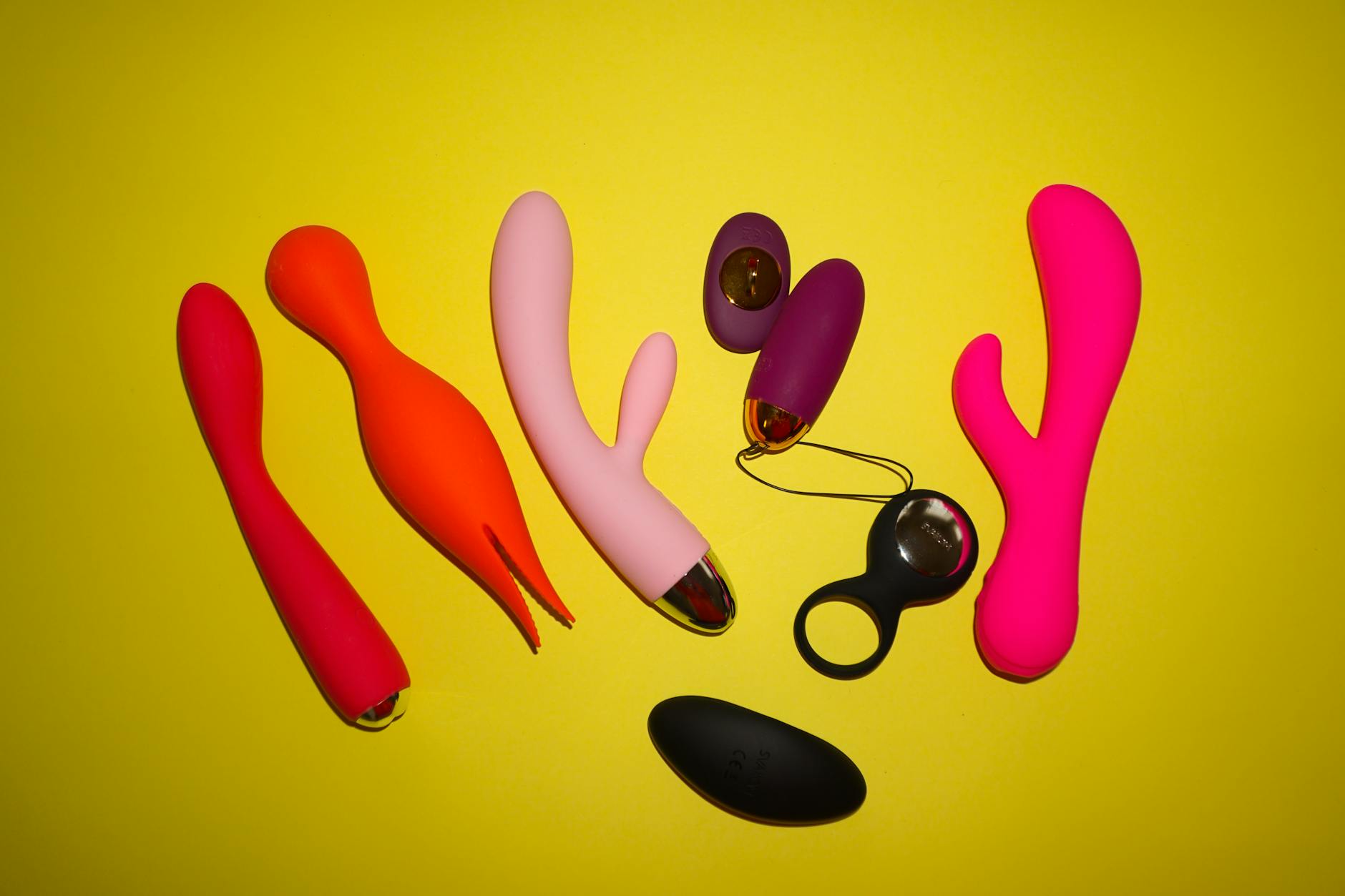 Hands holding a modern blue clitoral vibrator against a purple background